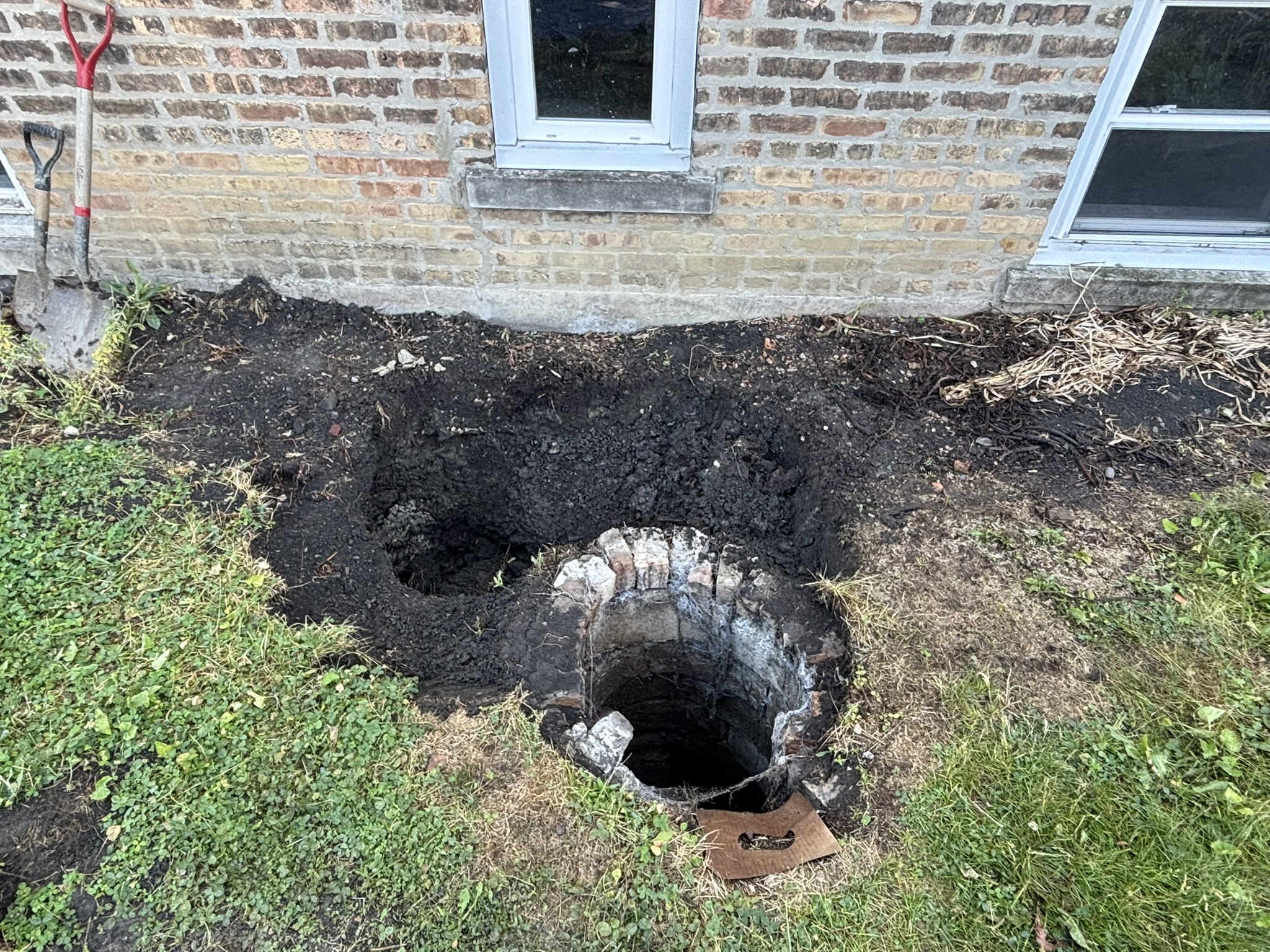Chicago catch basin before rebuild — old collapsed brick catch basin excavated next to a two-flat
