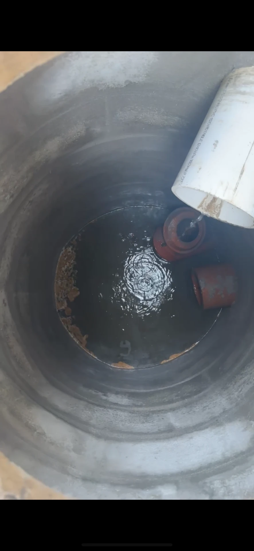 Chicago catch basin after rebuild — clean water flowing from the new PVC inlet into the rebuilt basin
