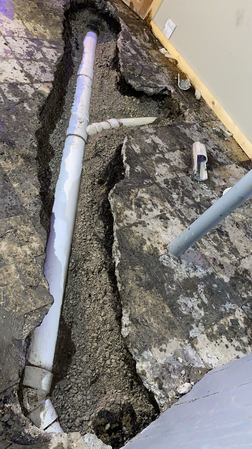 Chicago sewer repair in progress — new PVC line inside a two-flat with concrete floor cut open