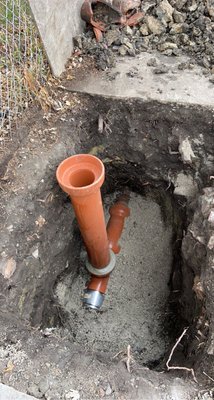 White PVC yoke fitting installed at a sewer cleanout