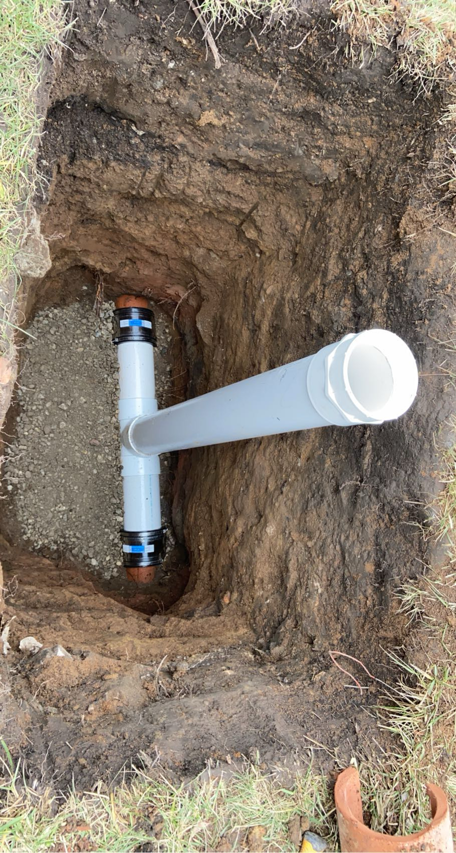 Chicago sewer line replacement — new white PVC tied into old clay pipe in an open trench