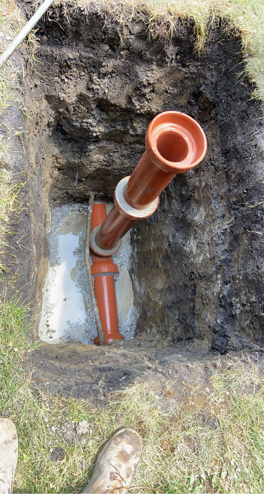 Orange PVC sewer cleanout riser set in concrete on a Chicago repair job