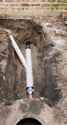Orange PVC cleanout riser installed in an excavated pit