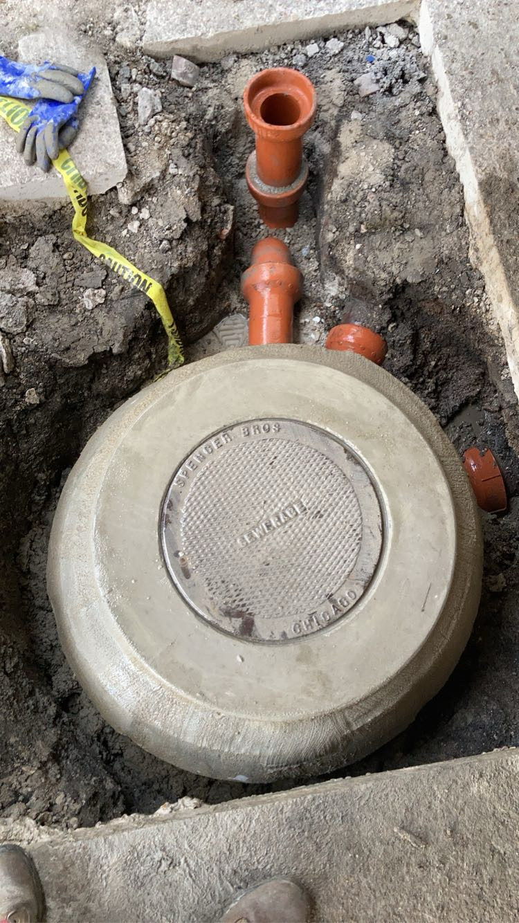 Chicago catch basin rebuild — Spencer Bros sewerage lid set on a freshly rebuilt basin with new clay pipe risers
