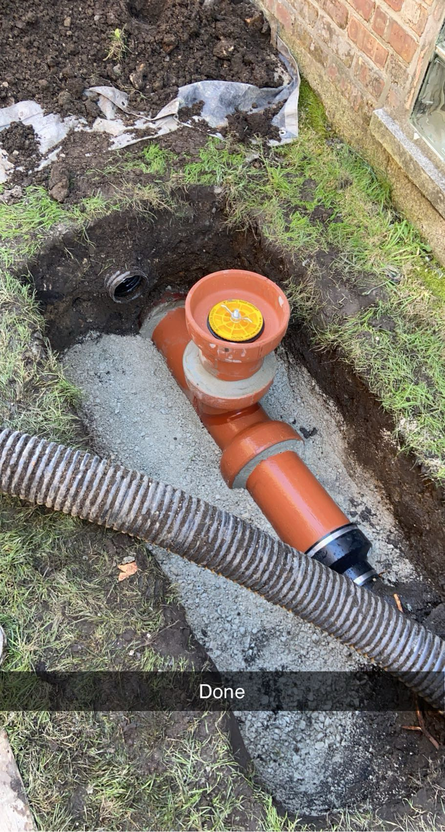 New cleanout riser with a gasketed cap set in concrete on the rebuilt side yard sewer line