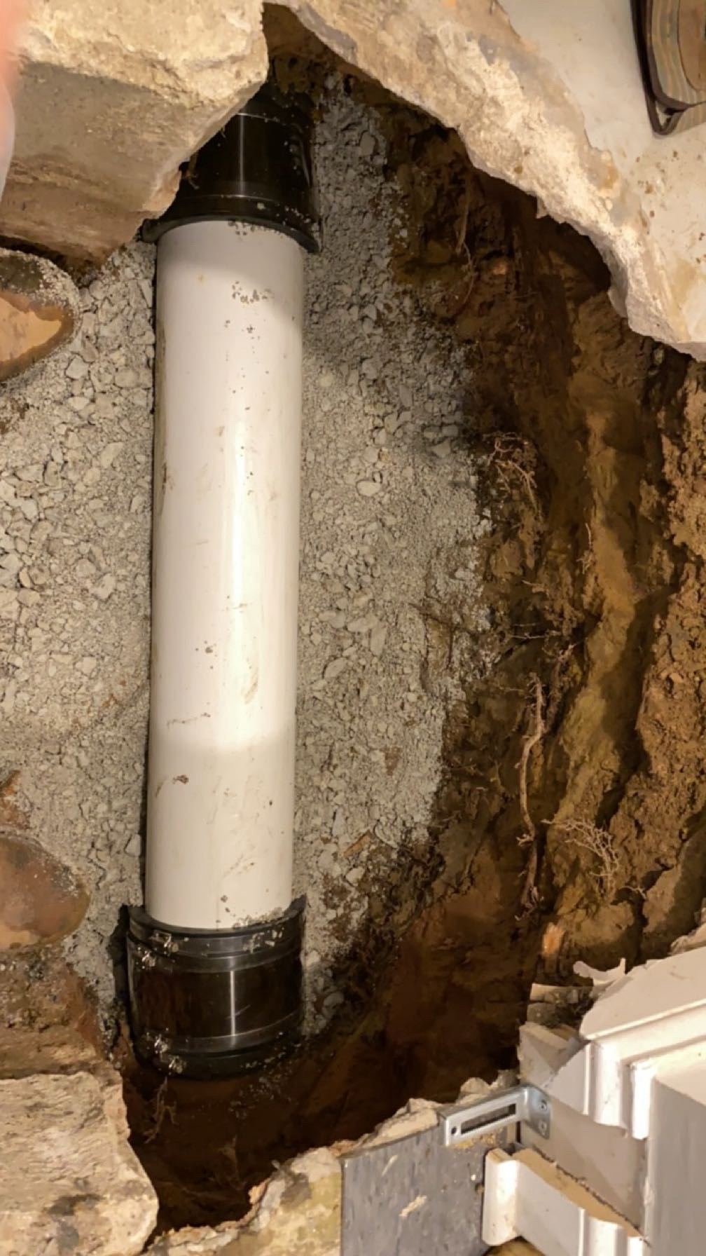 New PVC section set in the basement trench with shielded couplings on both ends over fresh gravel